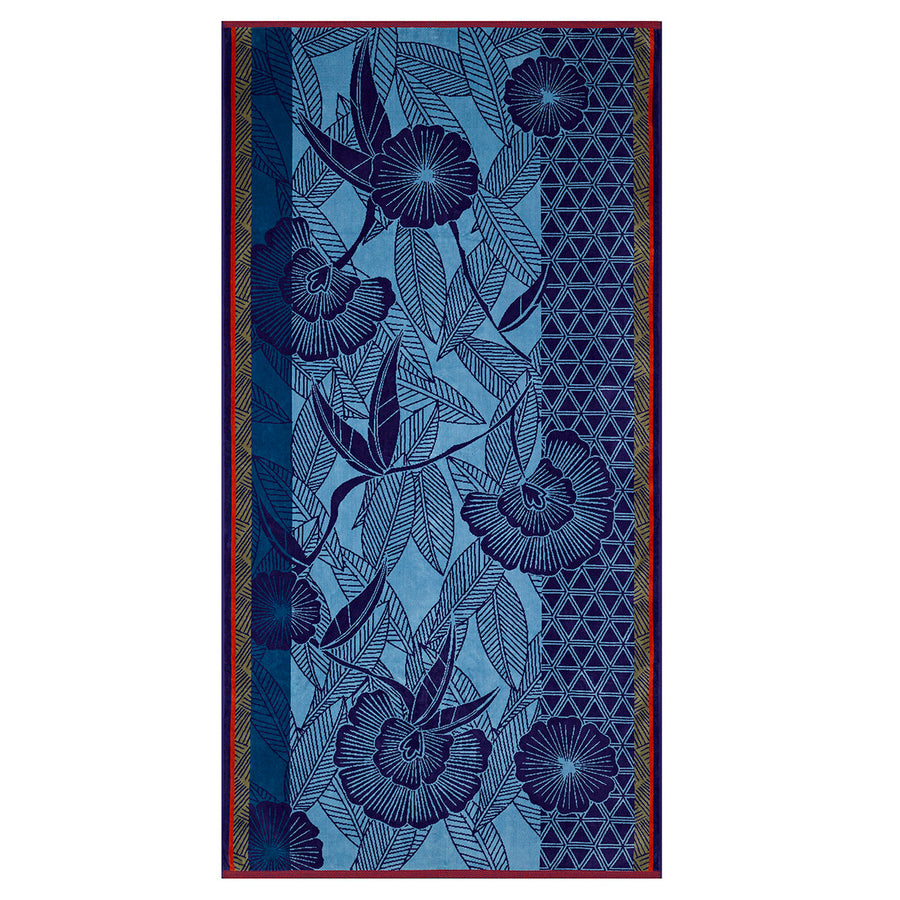 Blue beach towel featuring intricate floral and leaf patterns, with geometric designs on one side. Ideal for summer use.