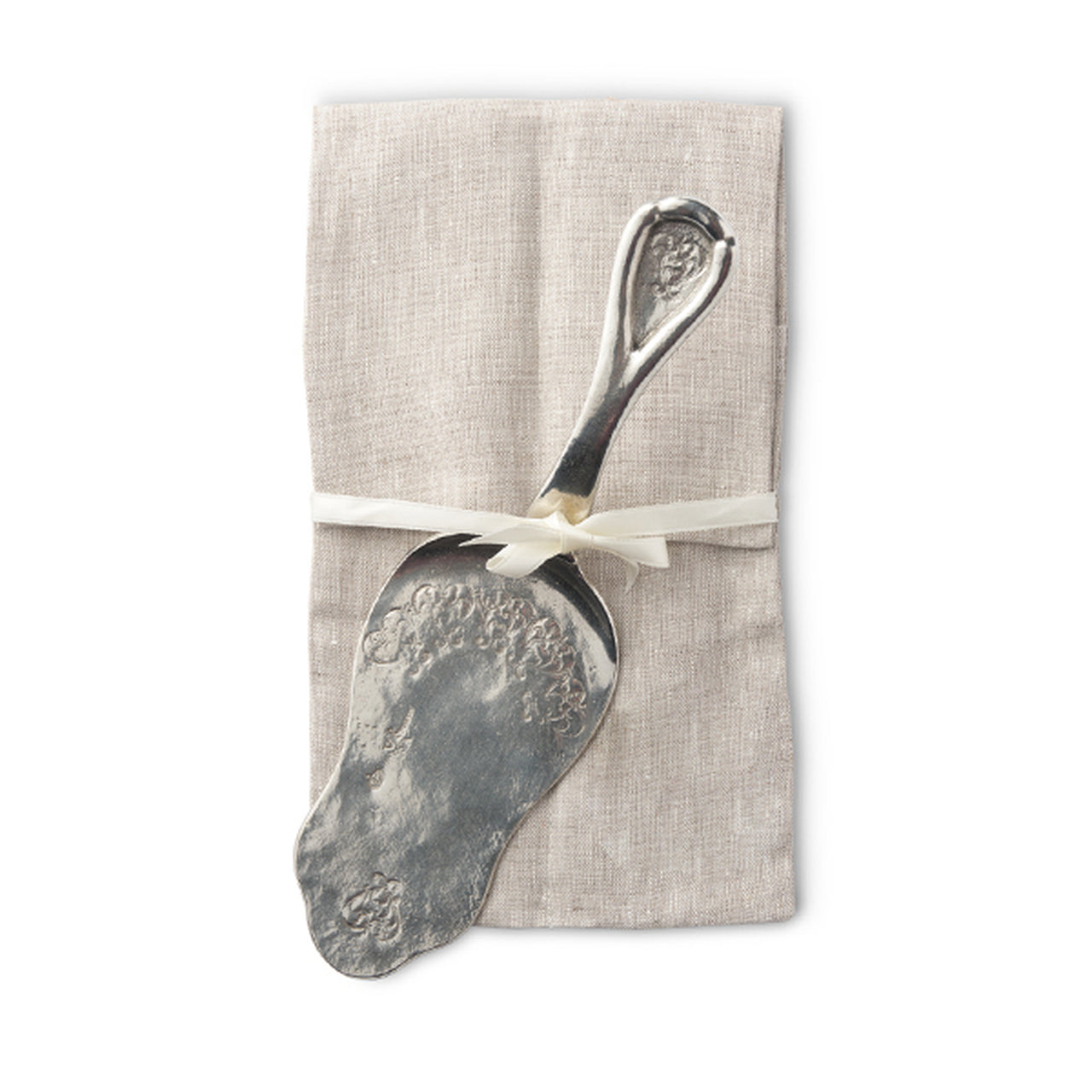 Vintage silver pastry server resting on a folded linen napkin, tied with a ribbon for an elegant presentation.