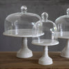 Three elegant Casafina glass domes on white pedestals, showcasing a classic design for displaying desserts or pastries.