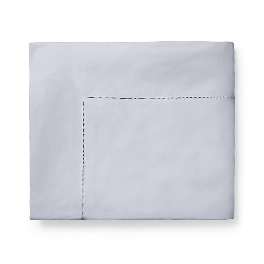 Sferra Celeste duvet cover in a soft light blue color with a subtle stitched border, elegantly folded.