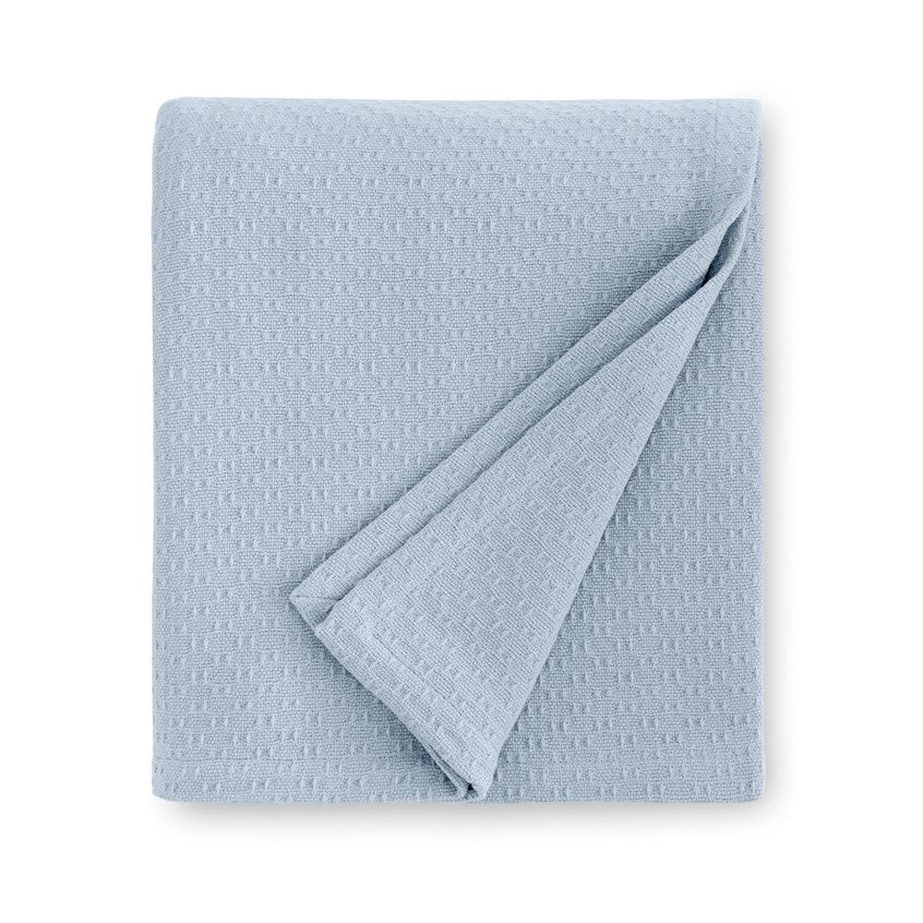 Soft powder blue SFERRA Corino blanket folded neatly, featuring a textured pattern for added depth and style.