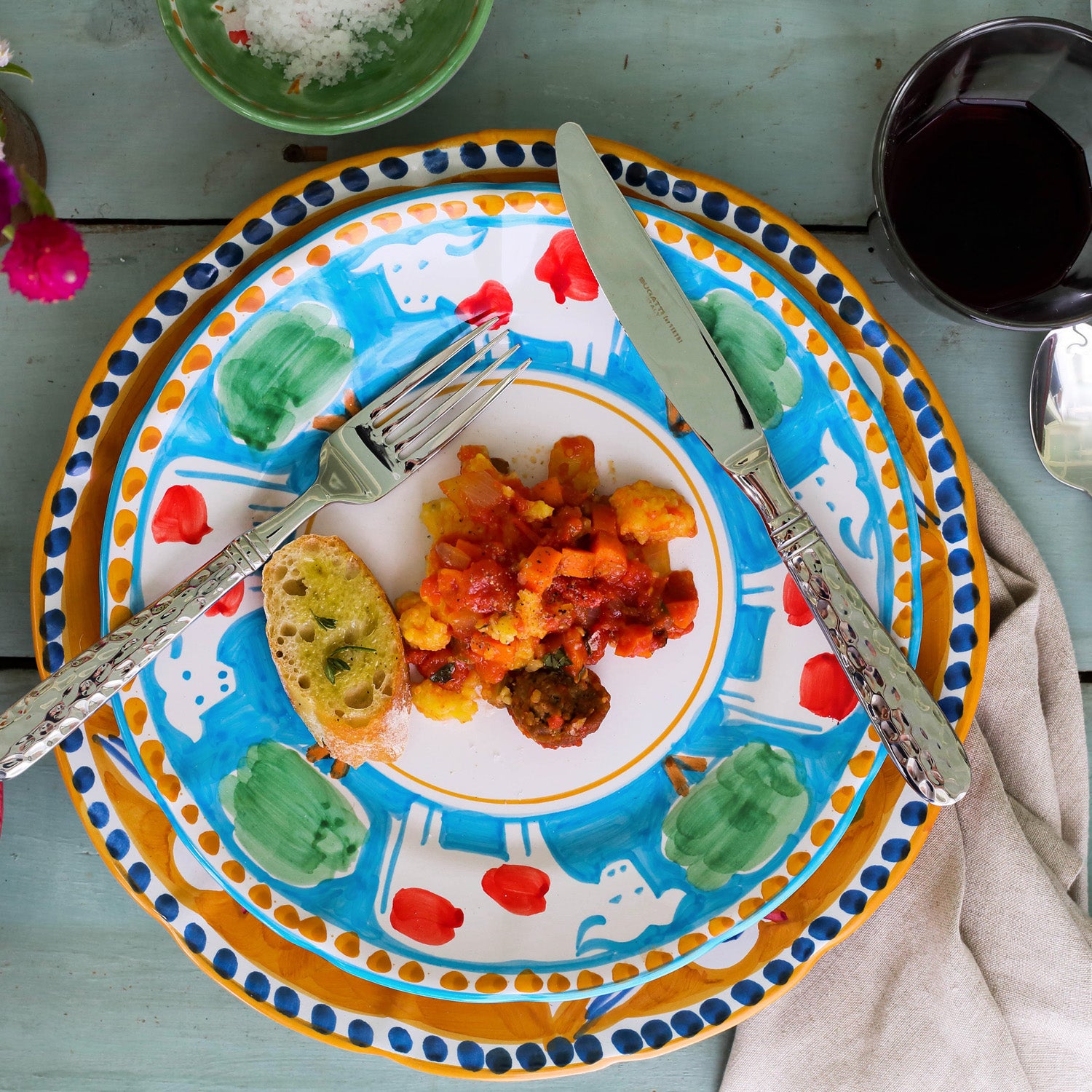 Vietri Campagna Pesce Pasta Bowl featuring vibrant colors, with a plate of pasta and bread on a rustic table setting.