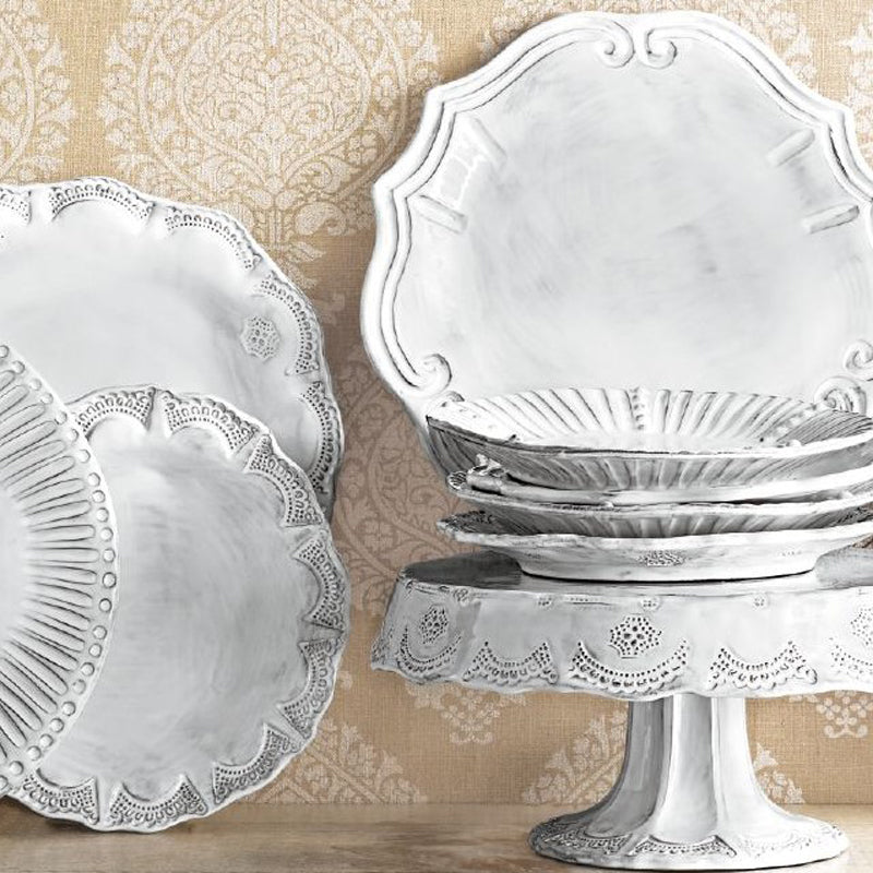 Vietri Incanto Lace European dinner plate set displayed on a decorative stand against a patterned background.